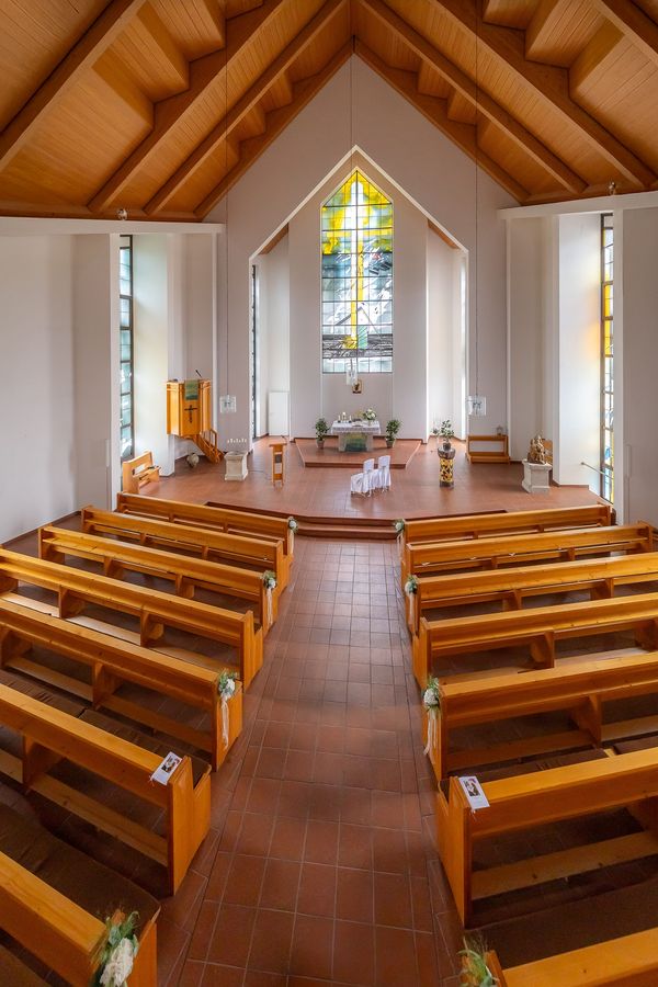 Innenraum der Kirche Völkershausen mit Holzbänken und Blumenschmuck