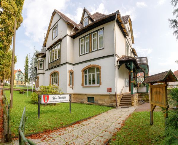 Rathaus Bad Liebenstein, weiße Villa mit Erker und Holzveranda, davor Rasen und Plattenweg